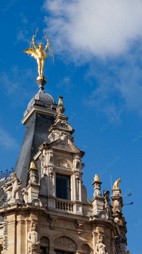 Golden figure statue on building roof 