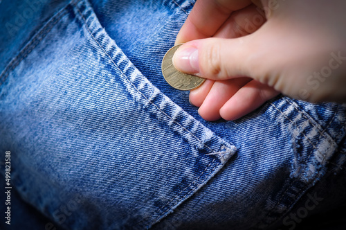 hand with gold coin in jeans pocket,savings concept