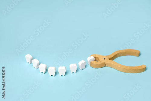 Tooth extraction with a dental instrument with forceps.  A model of teeth in the shape of a smile. Problems with wisdom teeth, toothache photo