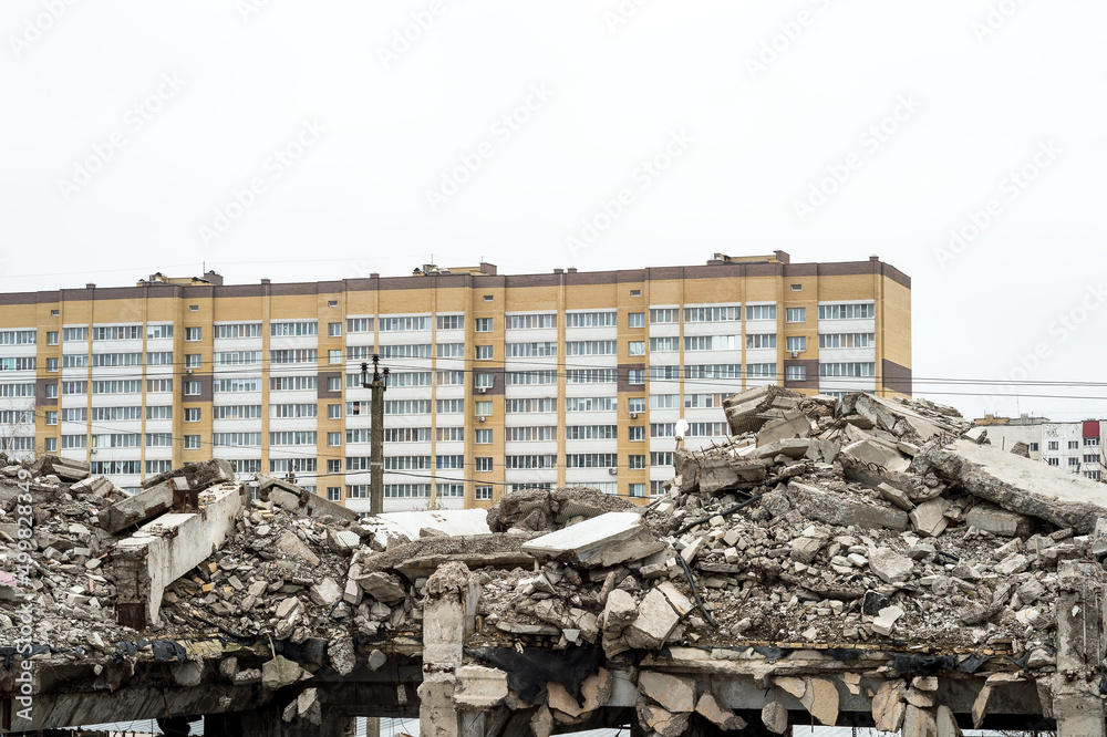 Concrete gray remains of a building against the background of city houses and a gray overcast sky. Background. The concept of destruction
