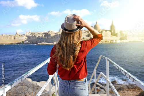 Tourism in Europe. Back view of traveler girl walking on stairs enjoying view of Valletta city, Malta. Young female tourist visiting southern Europe. photo