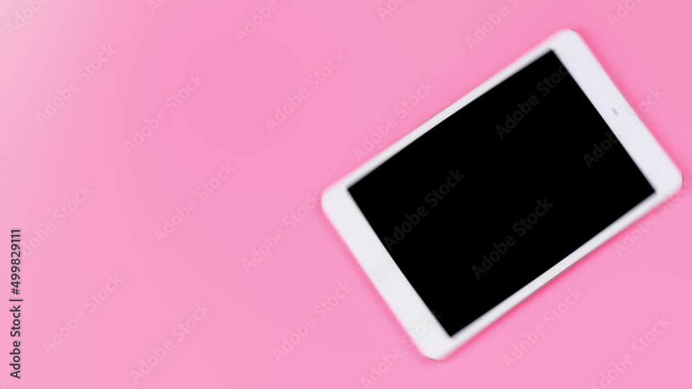 A simple pink background with a rotating tablet in a modern style. Background with empty space for text on the topic of modern technology. A simple pink background with a rotating tablet in a modern style. Background with empty space for text on the topic of modern technology.