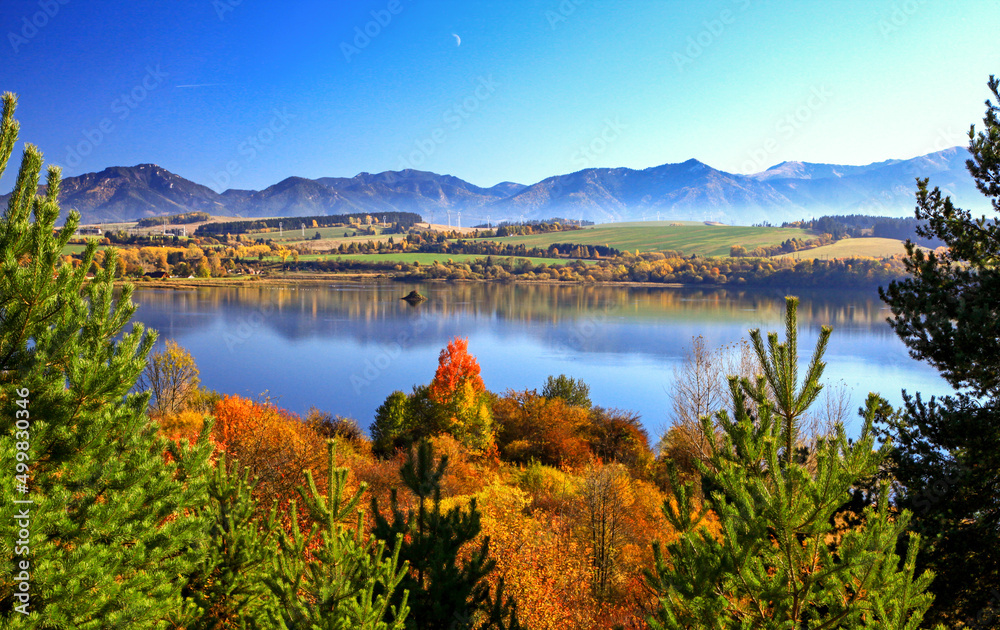 Autumn trees and mirror reflection of mountains in lake