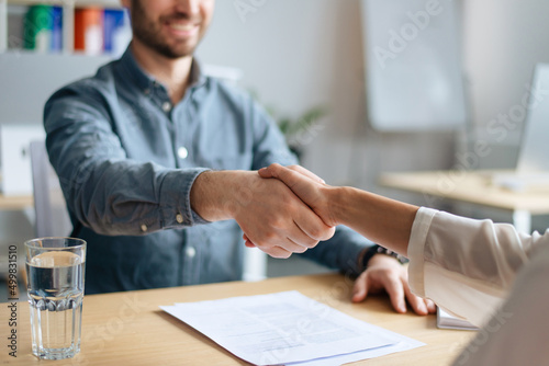 Cropped view of human resources manager shaking hands with successful vacancy applicant at office, closeup
