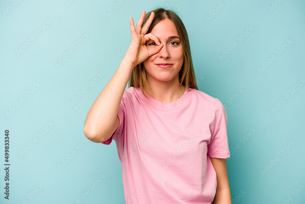Young caucasian woman isolated on blue background excited keeping ok gesture on eye. Young caucasian woman isolated on blue background excited keeping ok gesture on eye.