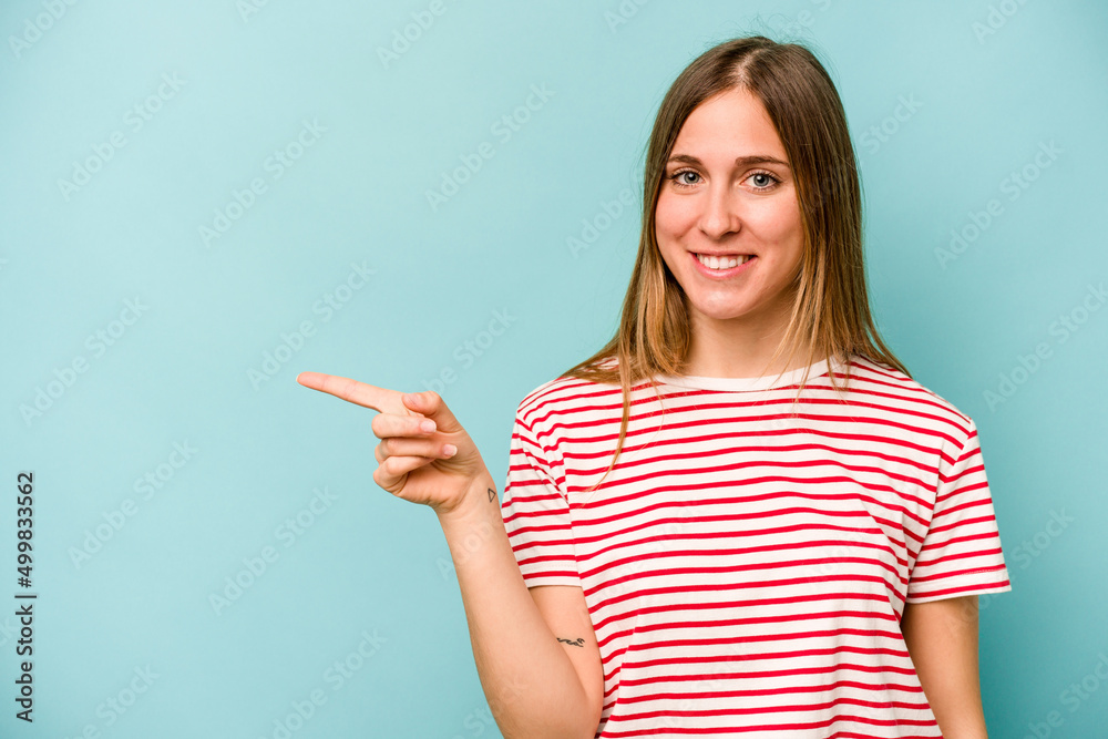 Young caucasian woman isolated on blue background smiling cheerfully pointing with forefinger away. Young caucasian woman isolated on blue background smiling cheerfully pointing with forefinger away.