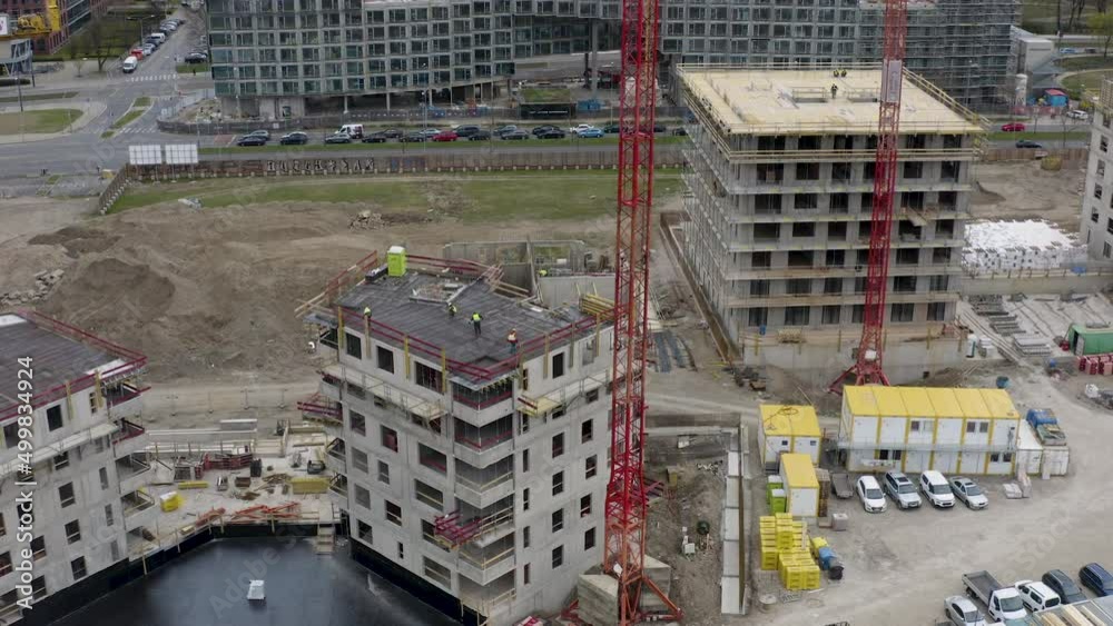 Construction site with tower cranes and workers on building rooftops
