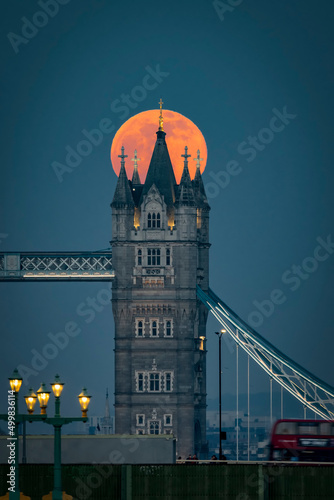 A big, red full moon rise behind the Tower Bridge of London, England during dusk photo