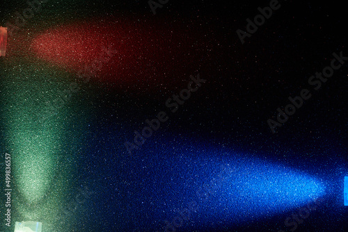 On a dark background in a small multi-colored grain, rays of blue turquoise and red light