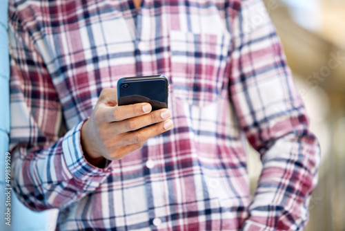 Hanging out during his free period. Closeup shot of an unrecognisable student using a cellphone on campus.