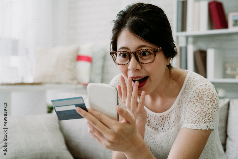 asian woman looking at phone screen in amazement opens her eyes and mouth wide can’t believe she win a big fortune in credit card prize draw. hand gesture and facial expression. asian woman looking at phone screen in amazement opens her eyes and mouth wide can’t believe she win a big fortune in credit card prize draw. hand gesture and facial expression.