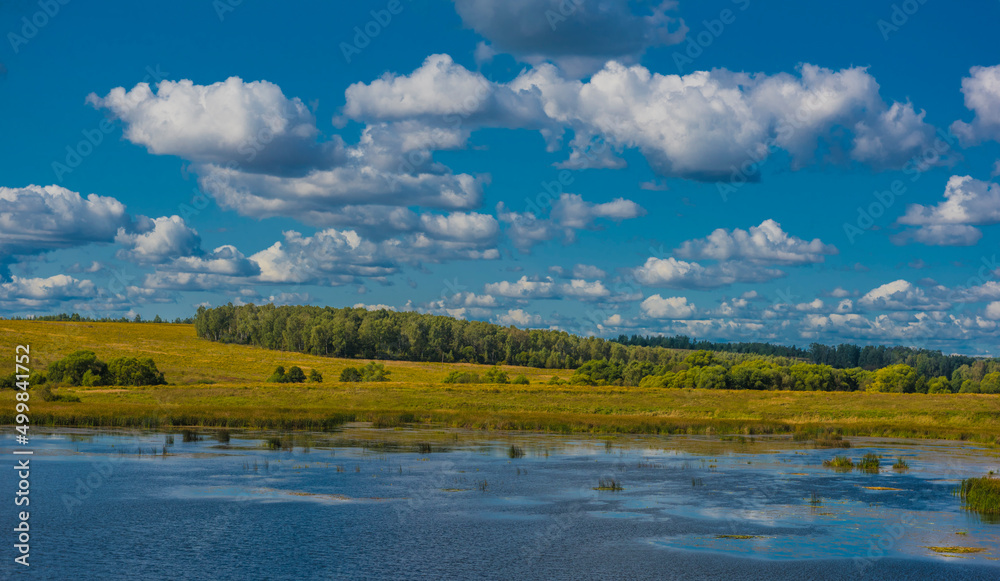 Clouds over the lake and field in autumn