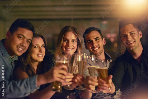 Heres to celebrating life. Portrait of a group of people toasting with their drinks at a nightclub.