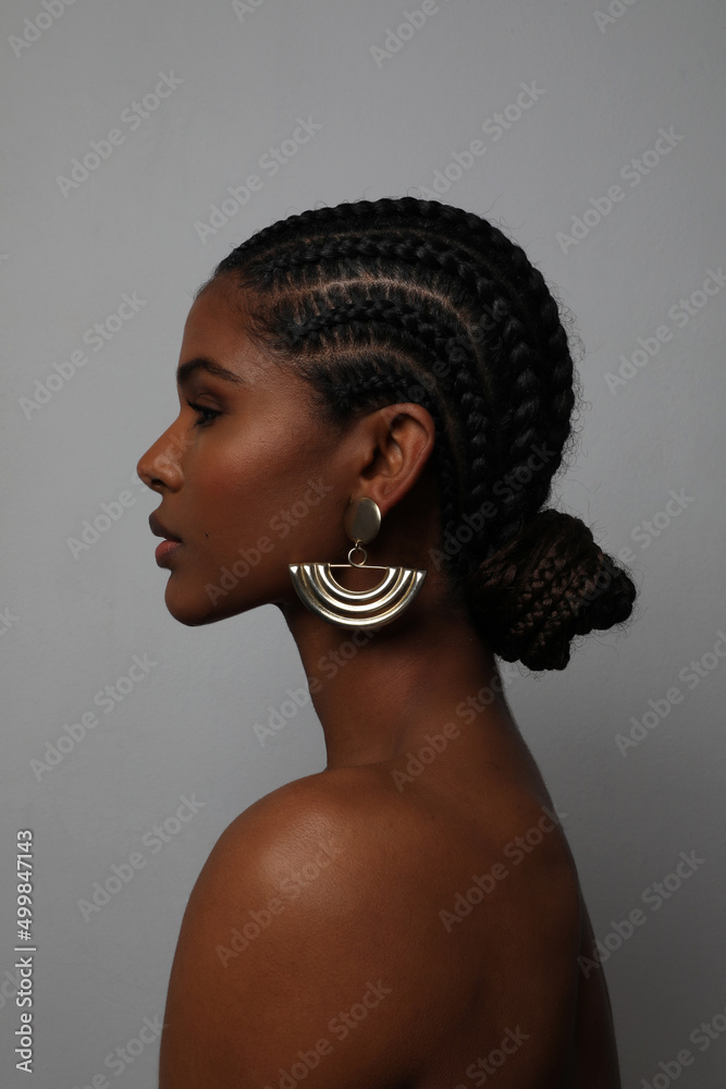Side profile portrait of African young woman with braids posing on grey wall. - obrazy, fototapety, plakaty 