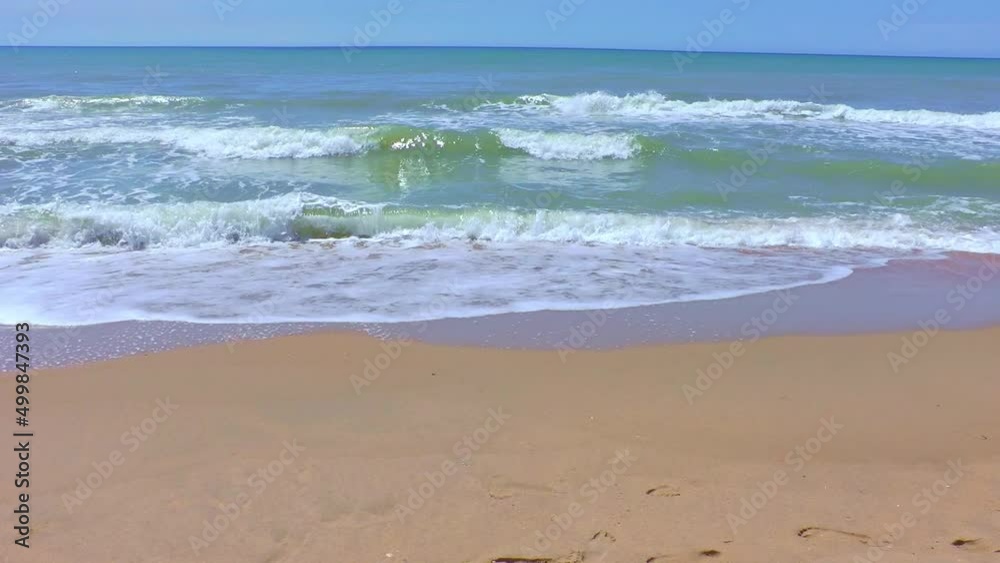 Sea wave with foam runs on a sandy beach on a sunny summer day. Sea wave with foam runs on a sandy beach on a sunny summer day.