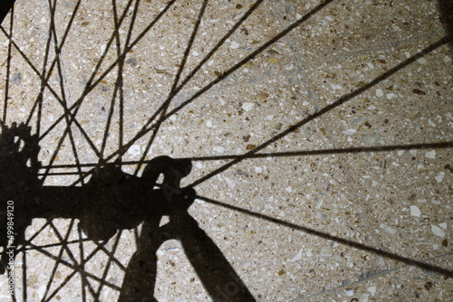 Sombra en el suelo de radios de acero para bicicletas que se refleja en la superficie en silueta en forma geomètrica de líneas negras que se cruzan, formando un hermoso patrón abstracto con fondo de s photo