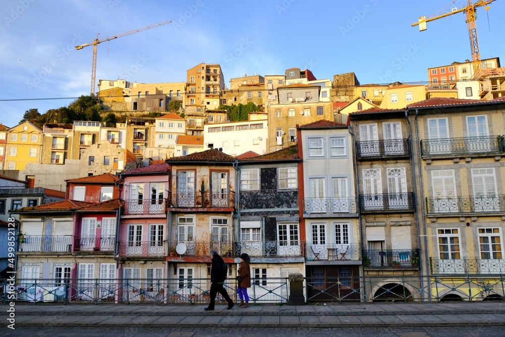 Scenery of street in Porto with traditional colorful buildings. Silhouettes of walking people. Portugal