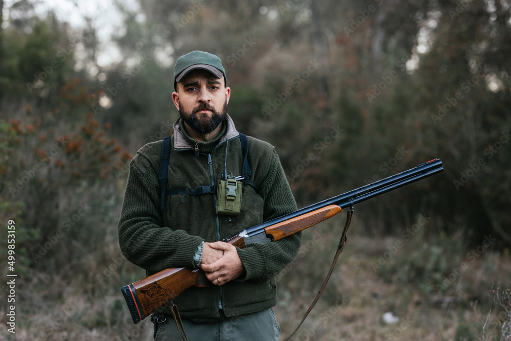 Fototapeta premium Confident man with rifle in woods during hunting