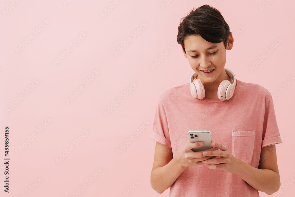 Asian boy wearing t-shirt smiling while using mobile phone Asian boy wearing t-shirt smiling while using mobile phone