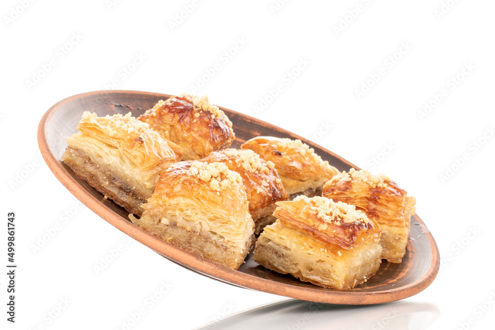 Sweet baklava classic on a clay dish, macro, isolated on a white background.