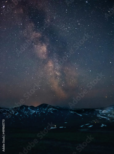 Milky way over the volcanoes of Kamchatka Russia, vertical frame. Beautiful starry sky with clusters of stars and nebulae over the mountains. The concept of travel, hiking.