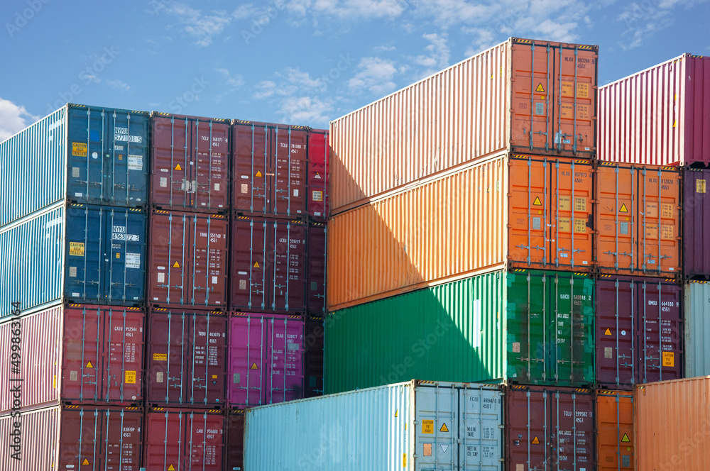 Shipping containers stacked against blue sky - obrazy, fototapety, plakaty 