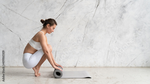 Obraz na plátně Banner of woman rolling her mat with both hands on after yoga class with copy sp