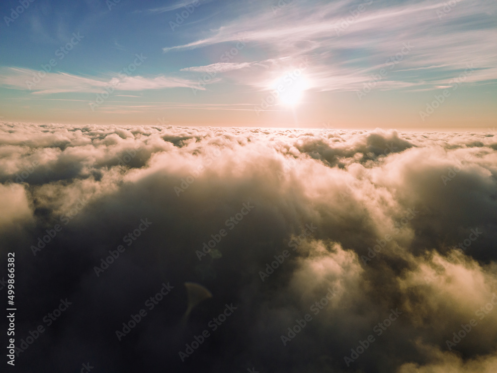 A magical sunset over the clouds. The rays of the sun beautifully pass through the clouds. Above the sky. Fluffy clouds at sunset thickly covered the sky. shooting at high altitude.