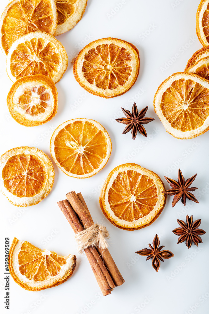 Sliced dried orange with cinnamon sticks and anise stars on white background. Top view. Sliced dried orange with cinnamon sticks and anise stars on white background. Top view.