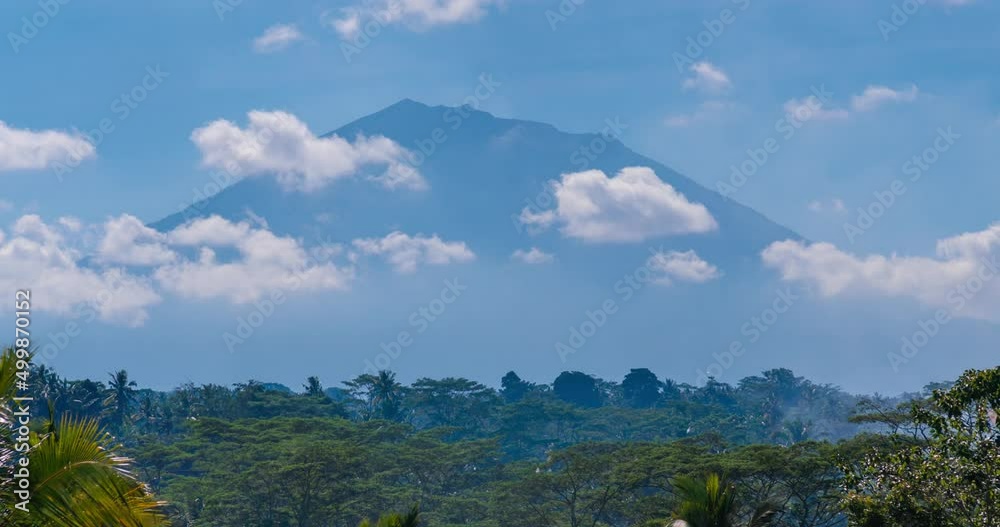 Timelapse of clouds moving from wind in blue sky with a mountain on background. trees, tropical area