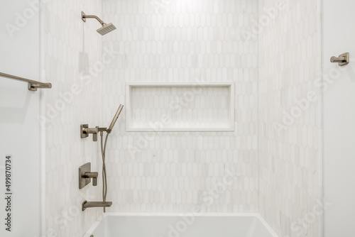 Contemporary Bathtub Enclosure with Gold Fixtures. White and gray tiled bathtub surround with gold fixtures and white tub.