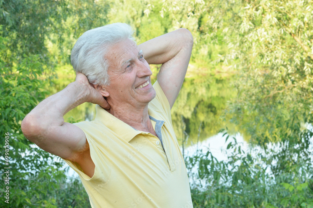 Smiling senior man posing in summer park Smiling senior man posing in summer park