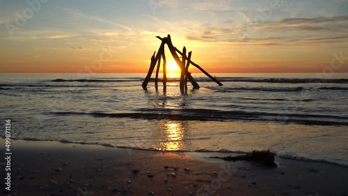 Sunset at the beach with a pile of wooden sticks in focus