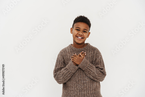 Black preteen boy smiling and holding hands on his chest photo