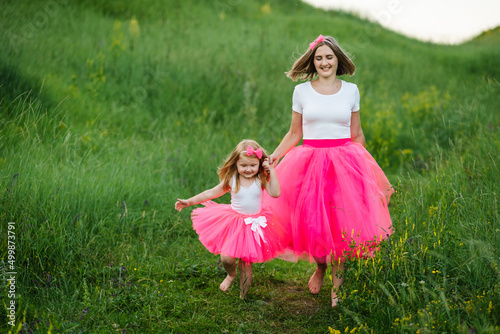 Young mother with a girl in the park. Young beautiful mom with her daughter in the same clothes. Family same look. Fashion style. Clothing for parent and child.
