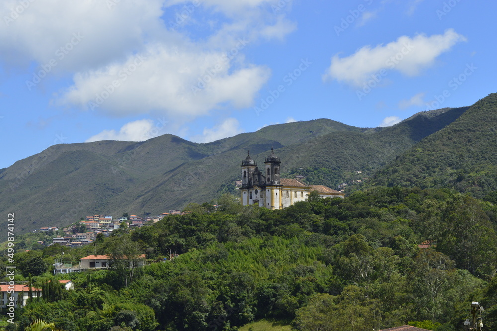 Igreja no meio da mata com montanhas ao fundo