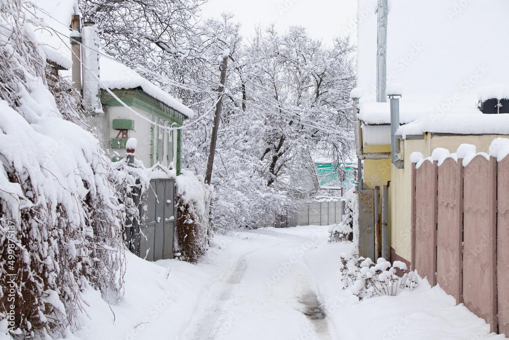 Street in the snow with one-story houses in the snow and roads along the street in Ukraine in the city of Dnipro, winter
