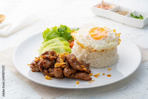 tir-Fried Pork with Garlic and pepper and cooked thai jasmine rice topped with fried egg in white plate,popular Thai food
