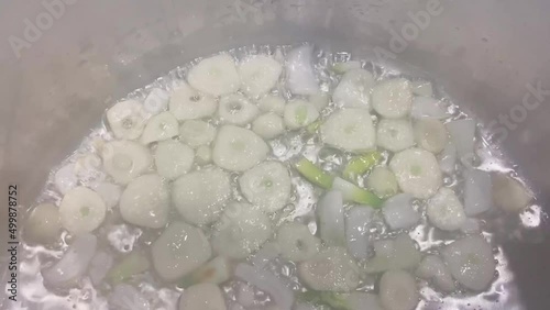 Close-up of garlic cloves cut into pieces, which are fried in boiling cooking oil
