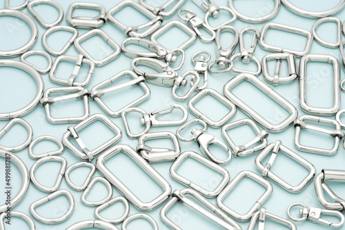 The heap of metal accessories for making bags and backpacks lying on a light blue background. Chrome-plated metal accessories and supplies for bags, backpacks. Handbags making, sewing accessories photo