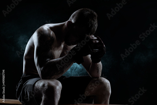 Kickboxer with overlays on his hands prays before the fight. The concept of mixed martial arts.