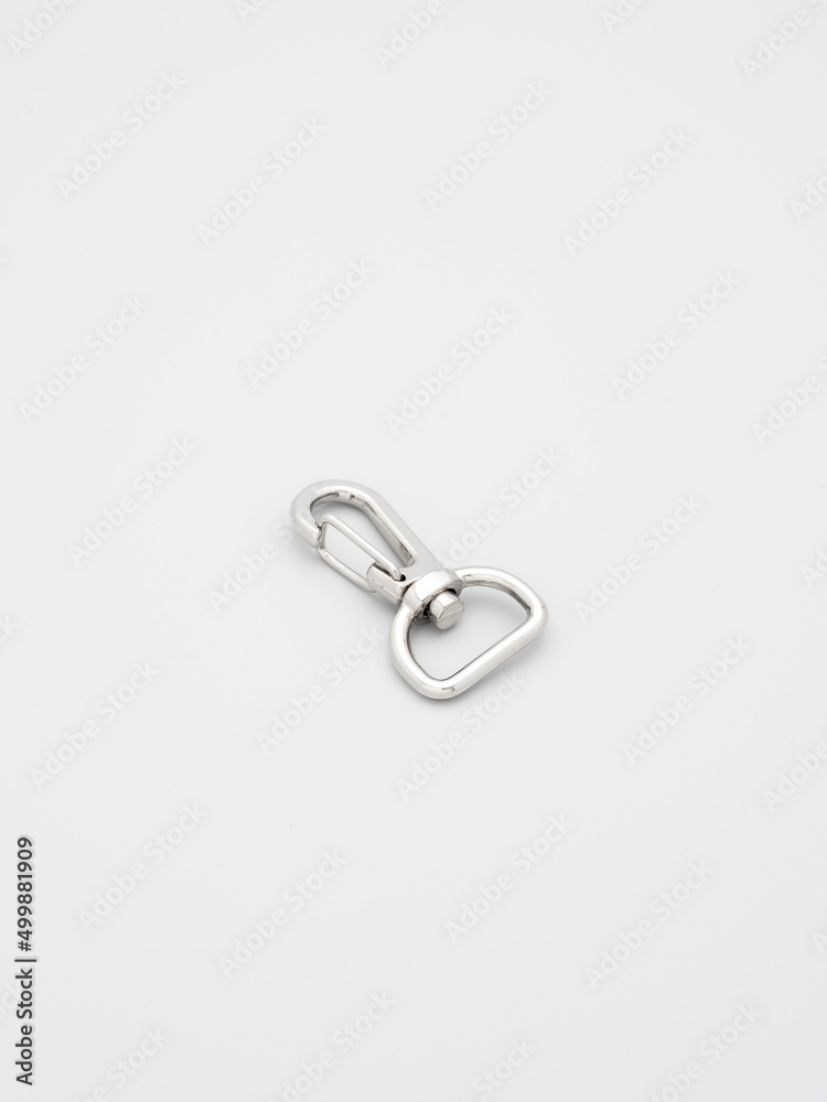 The heap of metal lobster claw clasp for making bags and backpacks lying on a gray background. Chrome-plated metal accessories and supplies for bags, backpacks. Handbags making, copy space The heap of metal lobster claw clasp for making bags and backpacks lying on a gray background. Chrome-plated metal accessories and supplies for bags, backpacks. Handbags making, copy space