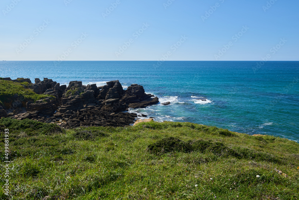 Cliffs surrounded by green vegetation under a blue sky.