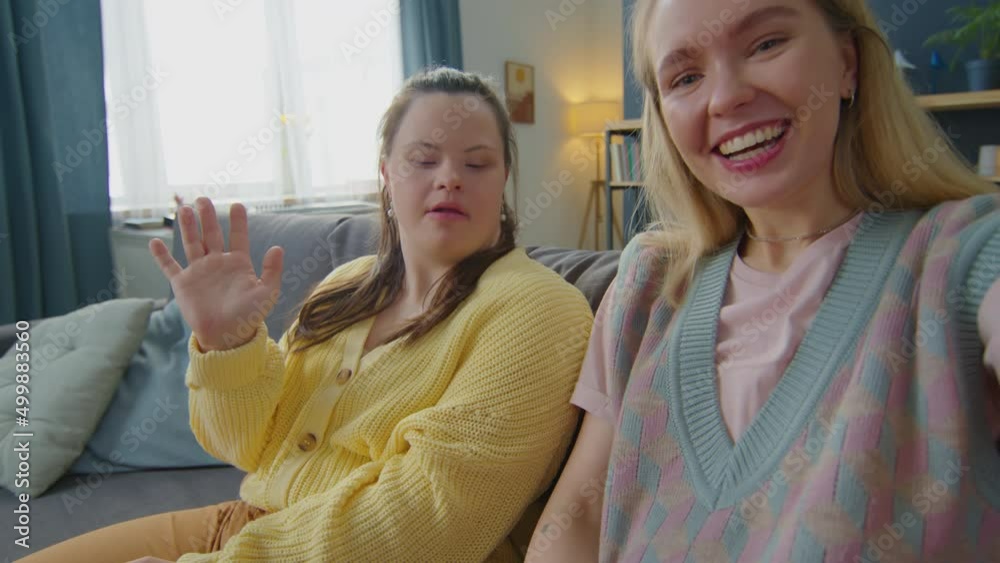 POV of young cheerful woman and girl with Down syndrome looking at camera, waving and chatting on online video call from home Stock Video | Adobe Stock