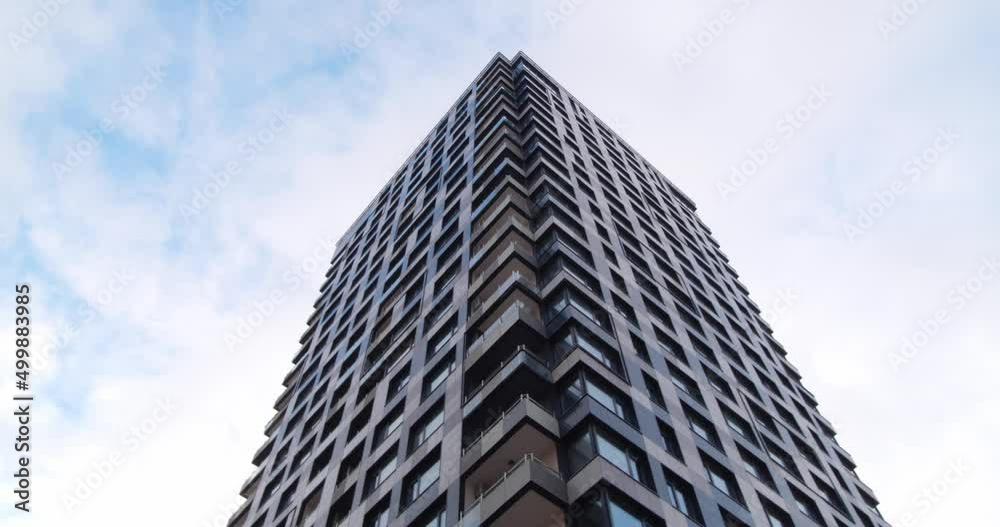 Skyscraper against cloudy sky, low angle view. Camera panning right Skyscraper against cloudy sky, low angle view. Camera panning right