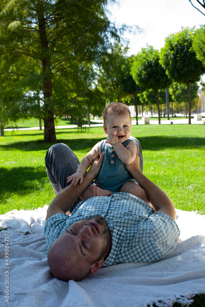 father plays with his little son in the park on the grass. Summer, fresh air. Family, fatherhood.