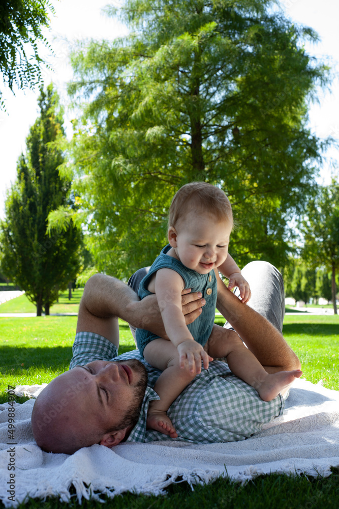 father plays with his little son in the park on the grass. Summer, fresh air. Family, fatherhood.