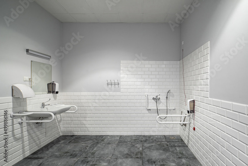 The interior of bathroom with facilities for the disabled. White bricks. Grey tile.