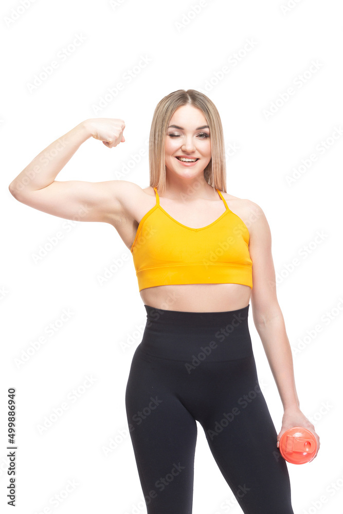 A beautiful, athletic, slim, smiling and cheerful woman in an orange top and black sweatpants in a comic form demonstrates her bicep muscles and holds a bottle of water. Lifestyle concept with sports A beautiful, athletic, slim, smiling and cheerful woman in an orange top and black sweatpants in a comic form demonstrates her bicep muscles and holds a bottle of water. Lifestyle concept with sports