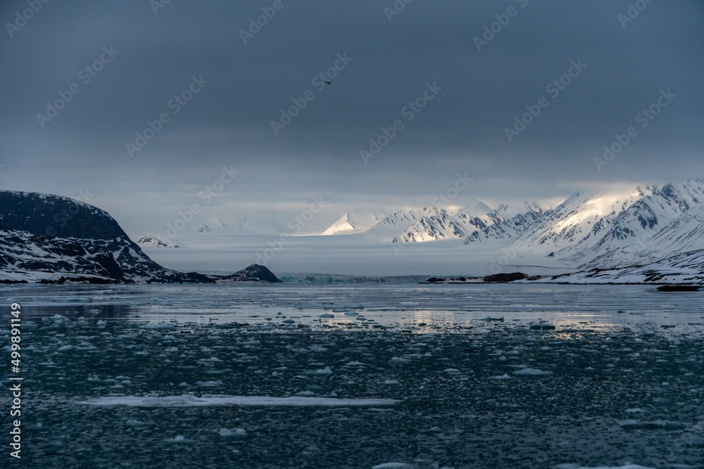 Snowy mountains with peaks in the clouds. In Svalbard, Norway. Global Warming.
